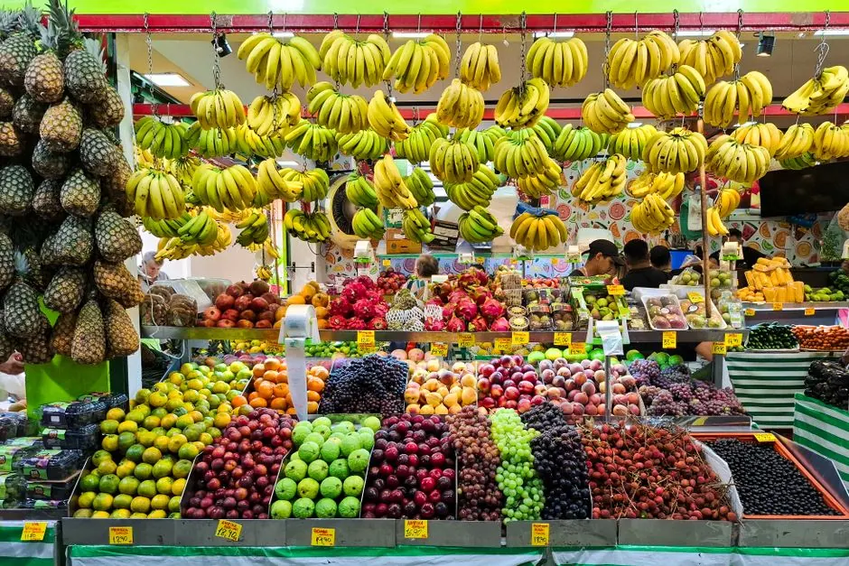 A colorful fruit market stall featuring an array of tropical fruits including bananas, pineapples, and apples.