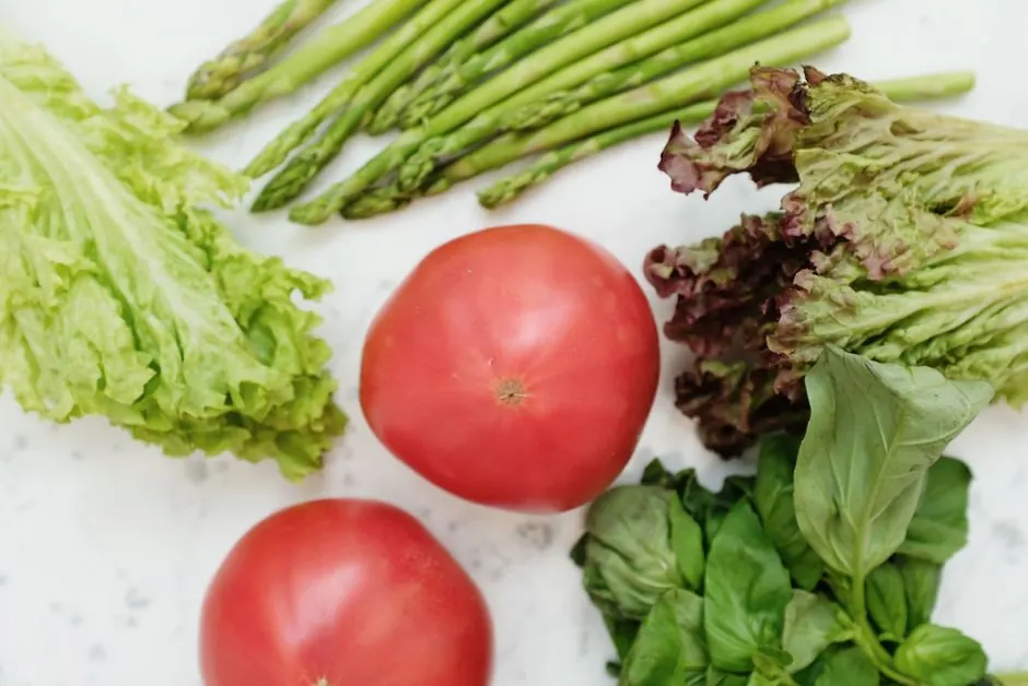 Top view of fresh asparagus, lettuce, basil, and tomatoes, highlighting healthy and nutritious ingredients.